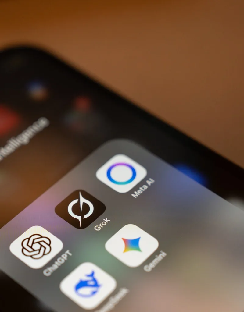 Smartphone screen displays ai app icons: chatgpt, grok, meta ai, gemini.